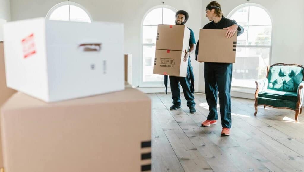 two moving company employees packing boxes