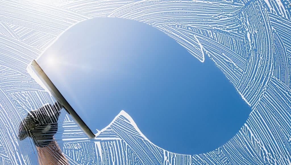 squeegee removing soap and water from a window pane