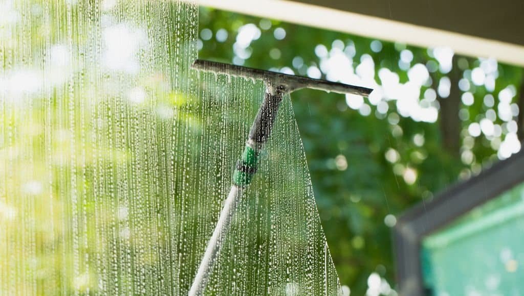 using a scraper to clean a window