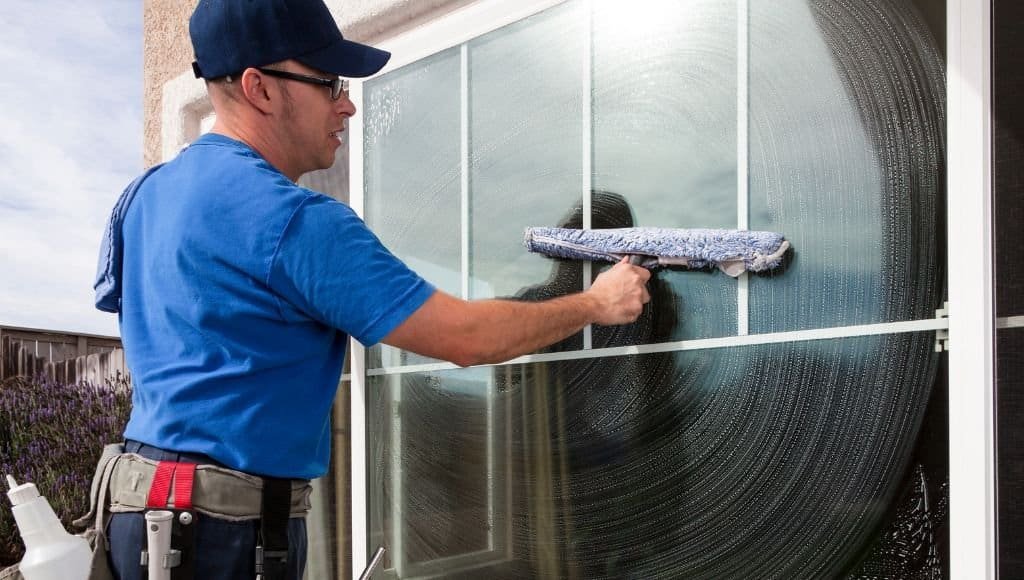 window washer cleaning windows with a scrubber