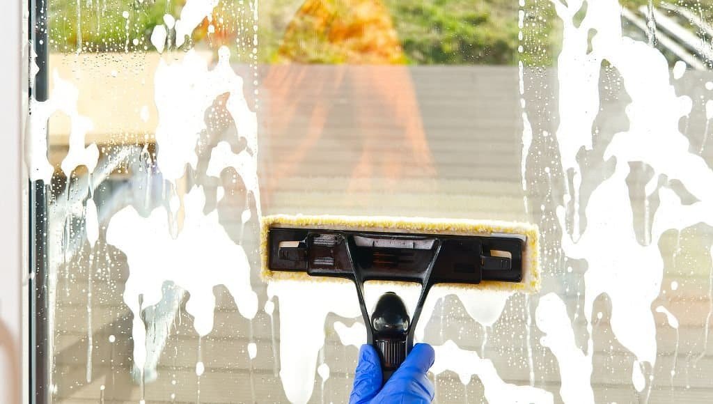 scrubber being used to wash glass window