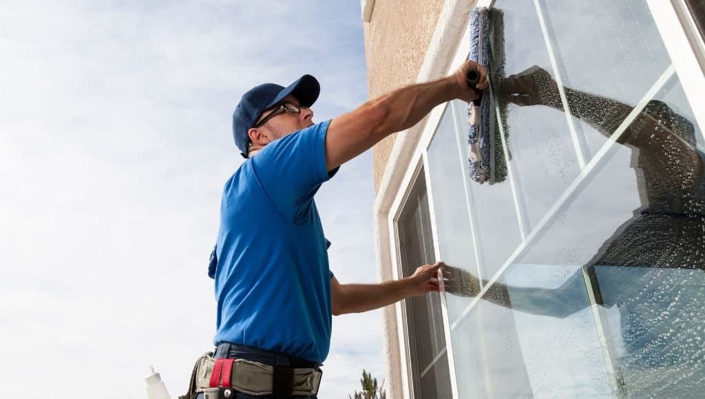 window cleaning business employee washing a window with a scrubber